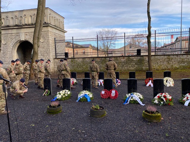 Personnel by headstones and poppy wreaths.